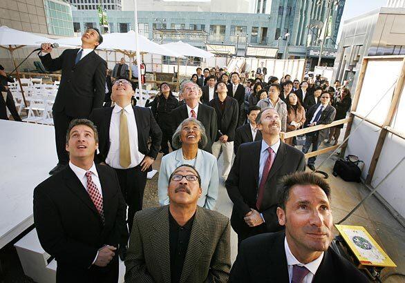 Los Angeles city councilman Herb Wesson bottom center, and LA County supervisor Yvonne Burke, above him, look up with others as they watch a construction crane hoist a citrus tree to the top of the new Solair development on the Wilshire corridor at Western Avenue during the building's dedication on Monday. Six miles of Wilshire Boulevard west of downtown was once a desirable business address where some of L.A.'s top financial firms clustered. But over the last five years, the grand boulevard is being remade as a fashionable address for residences. Several landmark office towers are being remade into luxury condos.