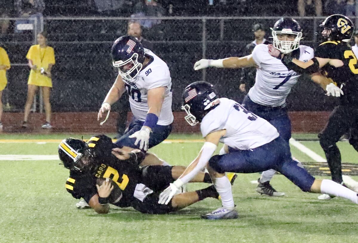 Newport Harbor's Trey Regitz (90) and Robby Crowell (33) bring down Capo Valley's Trey Kukuk (2) in the fourth quarter.