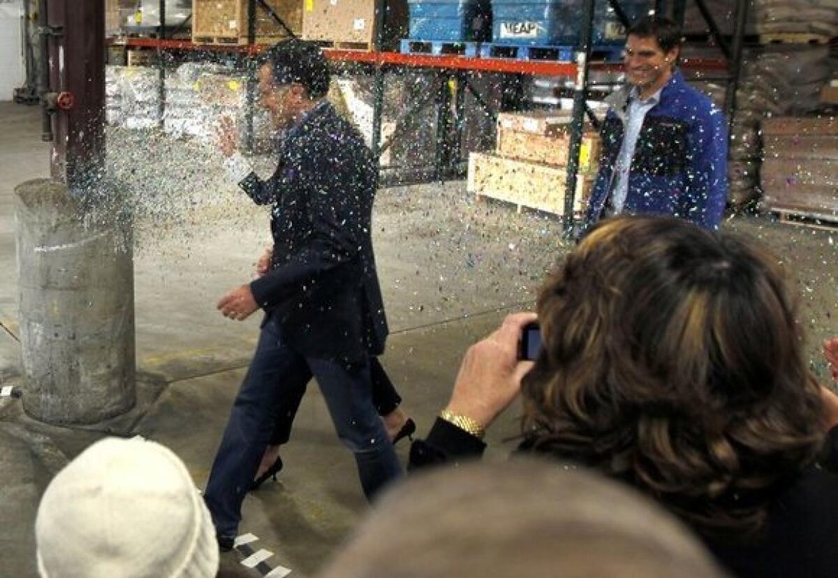 An activist, not pictured, throws a cup of glitter on Mitt Romney as he walks to the stage at the start of a campaign rally in Eagan, Minn., Wednesday, Feb. 1, 2012.