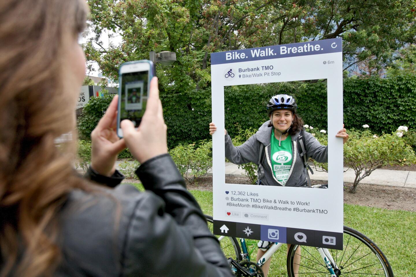 Walt Disney Studios employee and volunteer Cassi Basile, left, takes a photo of Warner Bros. employee Lindsey Cohen as she arrives at the Burbank Studios for the annual Bike and Walk to Work day, on Thursday, May 19, 2016. The event was sponsored by the Burbank Transportation Management Organization.