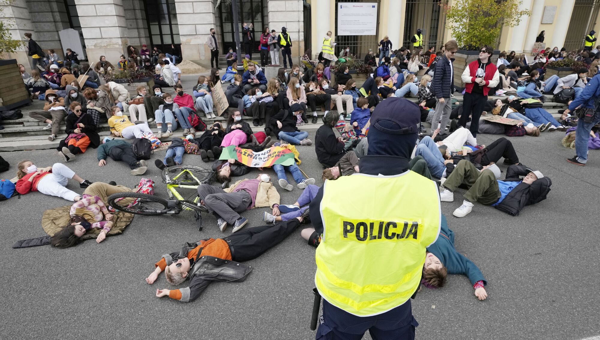 Activists lie in a street. A police officer looks on.