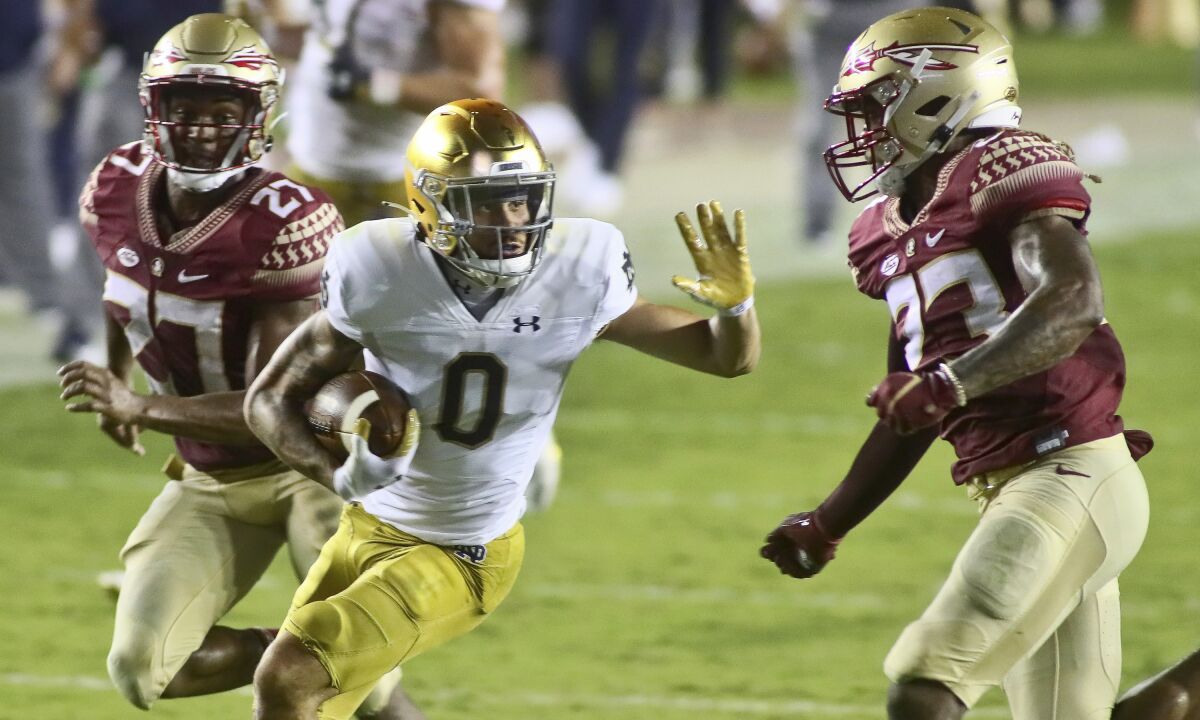 Notre Dame wide receiver Braden Lenzy tries to stiff arm Florida State defensive back Sidney Williams.
