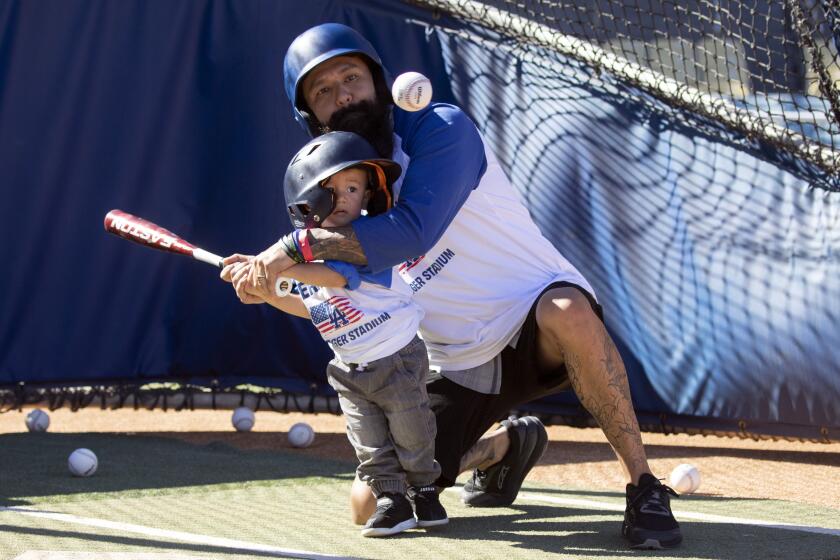 LOS ANGELES, CA - NOVEMBER 11: David Moyer, a Marine combat veteran, helps his son Logan, 1, with batting practice at Dodger Stadium during Veterans Day activities on Thursday, Nov. 11, 2021. (Myung J. Chun / Los Angeles Times)