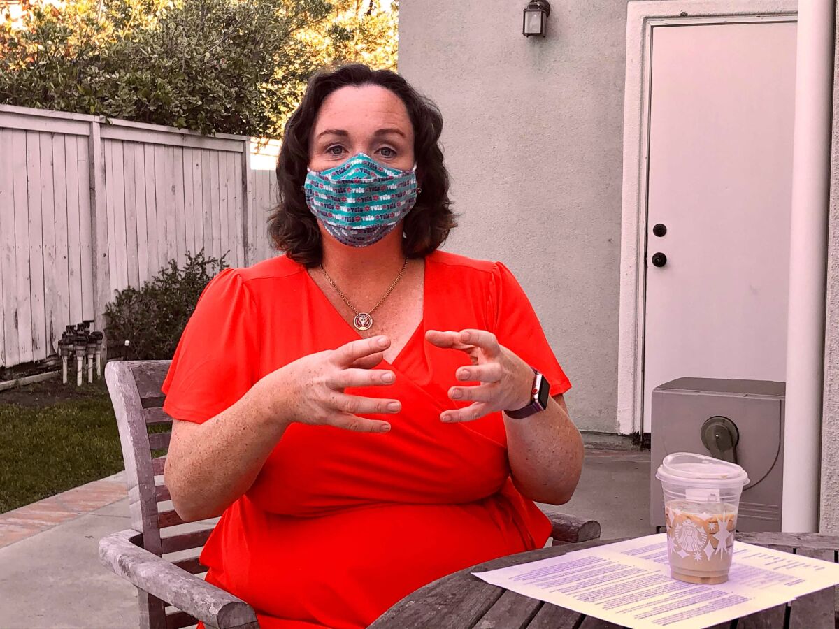 A seated woman wears a face mask outdoors.
