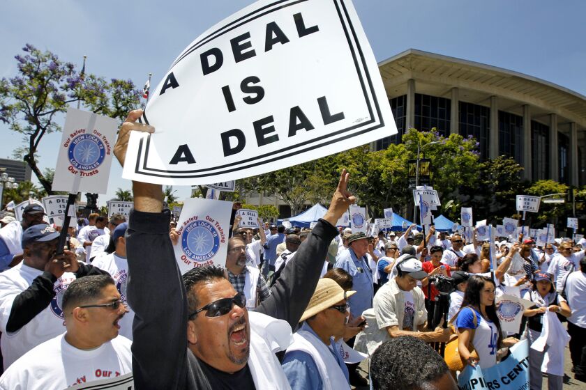 Union members and Department of Water and Power workers including Anthony Soltero, third from left, rally outside the Department of Water and Power in downtown Los Angeles.