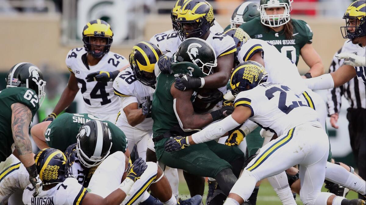 Michigan State's LJ Scott is tackled by the Michigan defense during a second-half run at Spartan Stadium on Saturday in East Lansing, Mich. Michigan won the game 21-7.