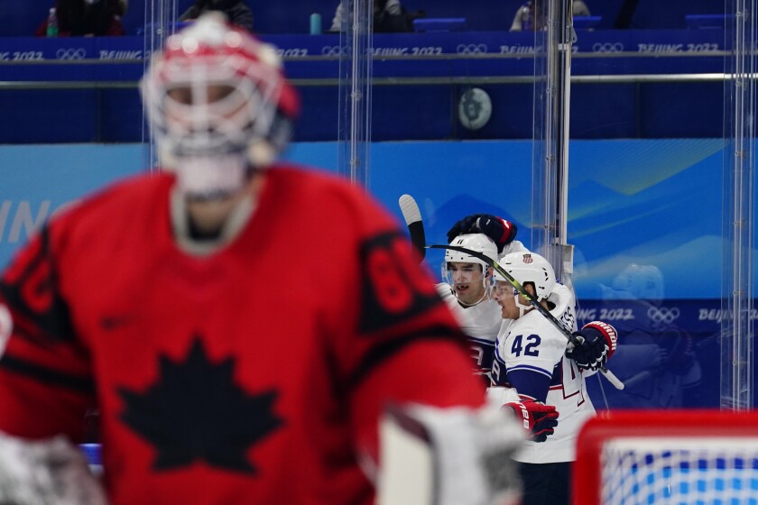 United States players Aaron Ness (42) and Kenny Agostino (11) celebrate after teammate Andy Miele scored a goal against Canada goalkeeper Eddie Pasquale, left, during a preliminary round men's hockey game at the 2022 Winter Olympics, Saturday, Feb. 12, 2022, in Beijing. (AP Photo/Matt Slocum)