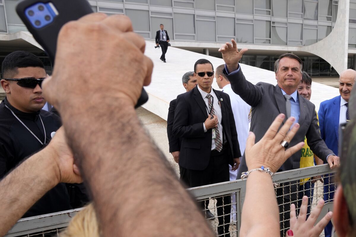 Brazilian President Jair Bolsonaro waves to supporters outside Planalto presidential palace in Brasilia, Brazil, Monday, Sept. 6, 2021. (AP Photo/Eraldo Peres)