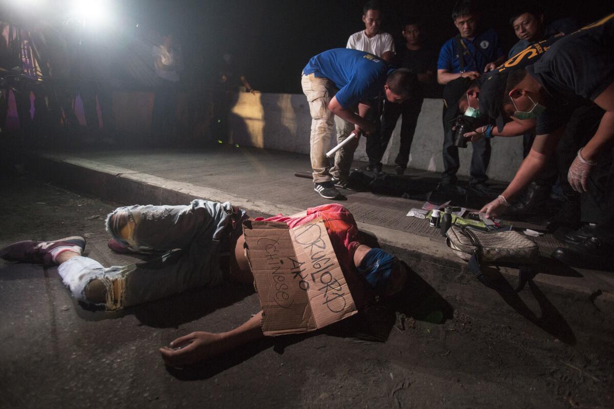 A victim of summary execution has packing tape wrapped over his head and a sign on his chest "I am a Druglord (Chinese)" along a bridge in the Tondo District of Manila, on July 28.