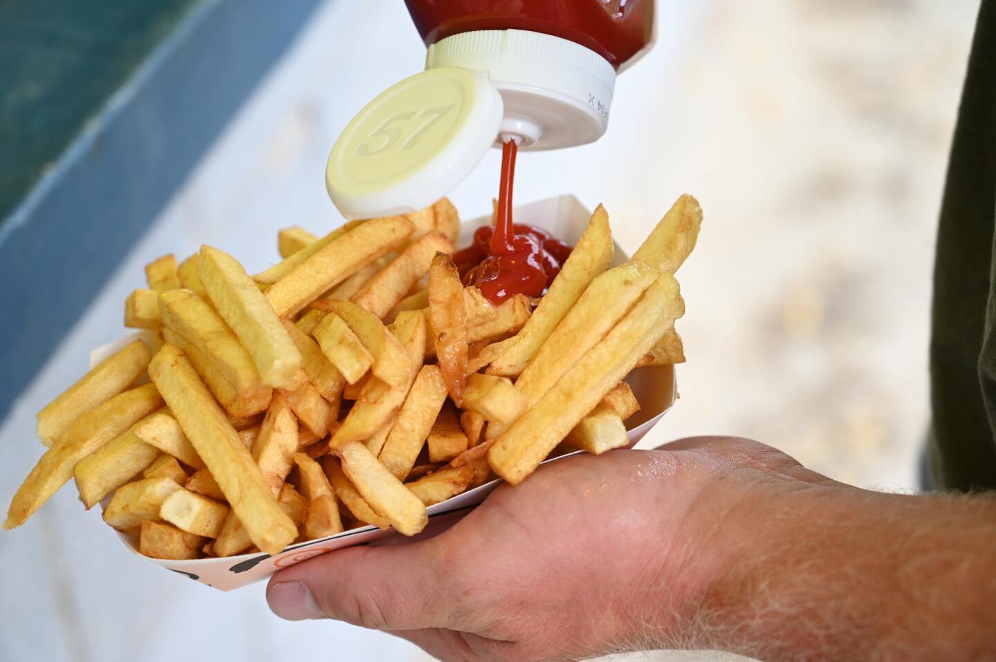 A customer adds ketchup to an order of fries during the carnival at Reese & Community Volunteer Fire Company on Tuesday, July 16.