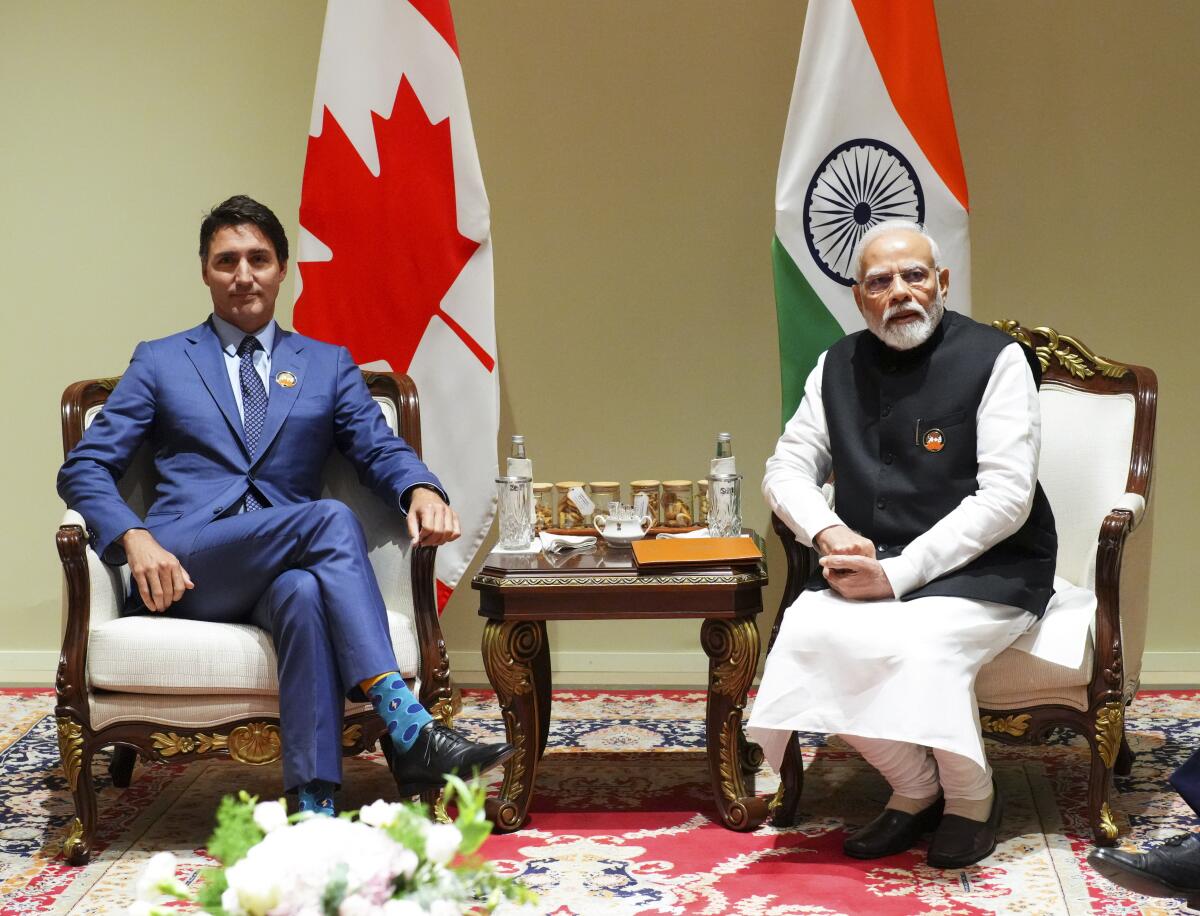  Justin Trudeau and Narendra Modi sit in front of their countries' flags.