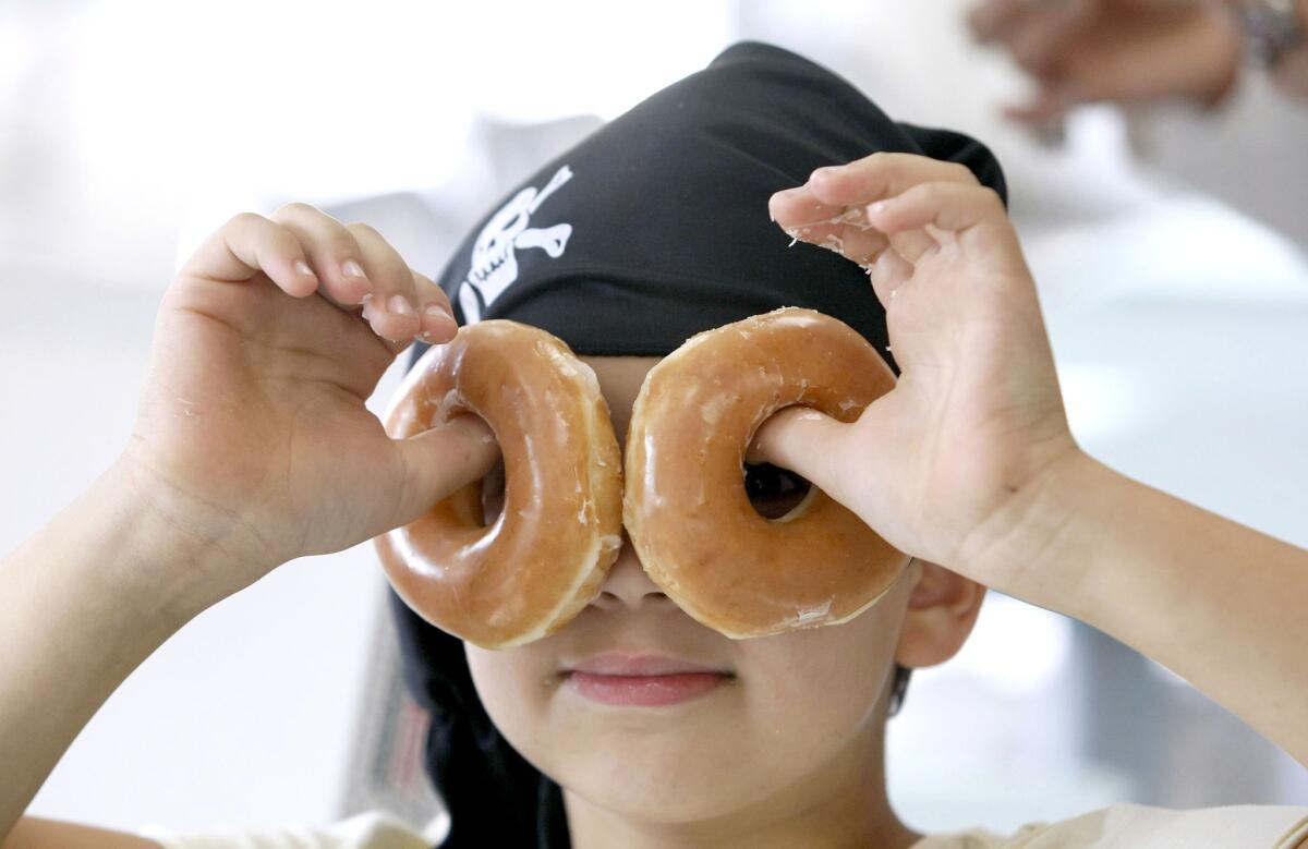 Micah Seidman of Sylmar, dressed like a pirate, plays a little bit with some of his free dozen doughnuts before eating them at the Burbank Krispy Kreme Doughnuts on International Talk Like A Pirate Day on Thursday, Sept. 19, 2013. Those talking like a pirate got a free doughnut and those dressed like a pirate got a free box of doughnuts.