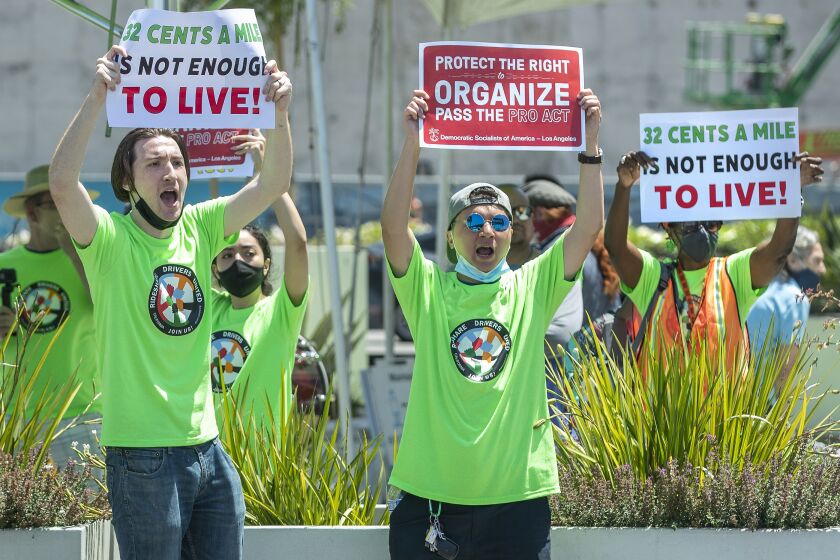 LOS ANGELES, CA - JULY 21, 2021: Joseph Stellitano, 26, left, who said that he has driven for Uber and Lyft for the past 4 years, is joined by other rideshare drivers and organiziers as they try to get the attention of rideshare drivers arriving at LAX-IT, the rideshare pickup location at LAX, yelling out to the drivers to turn off their apps and join the strike. The strike was aimed to push congress to pass the protect the right to organize act, proposed federal legislation that allows contractors to unionize if they choose. Stellitano said that he stopped driving for Uber and Lyft a month ago because it doesn't pay enough. (Mel Melcon / Los Angeles Times)