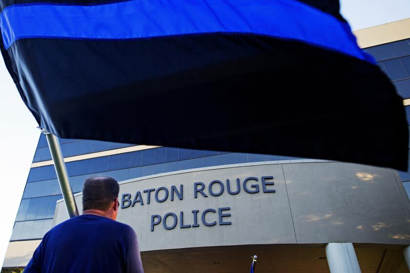 FILE - Brian Armoney of Baton Rouge holds a flag following a "Law Enforcement Support" ride in front of the Baton Rouge Police headquarters in Baton Rouge, La. Tuesday, July 19, 2016. The embattled Baton Rouge Police Department on Friday, Sept. 29, 2023, announced the arrest of three of its own officers, including a deputy chief, on charges they covered up a 2020 episode in which a suspect was struck and Tased during a strip-search in a department bathroom. (AP Photo/Max Becherer, File)
