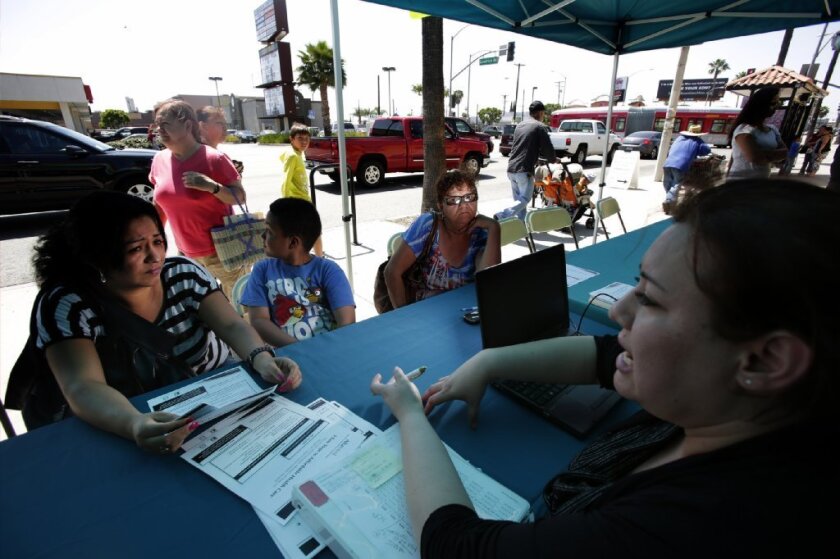 A new report predicts a sharp drop in uninsured residents in Los Angeles by 2016. Above, people sign up under the health law in April in Southeast L.A.