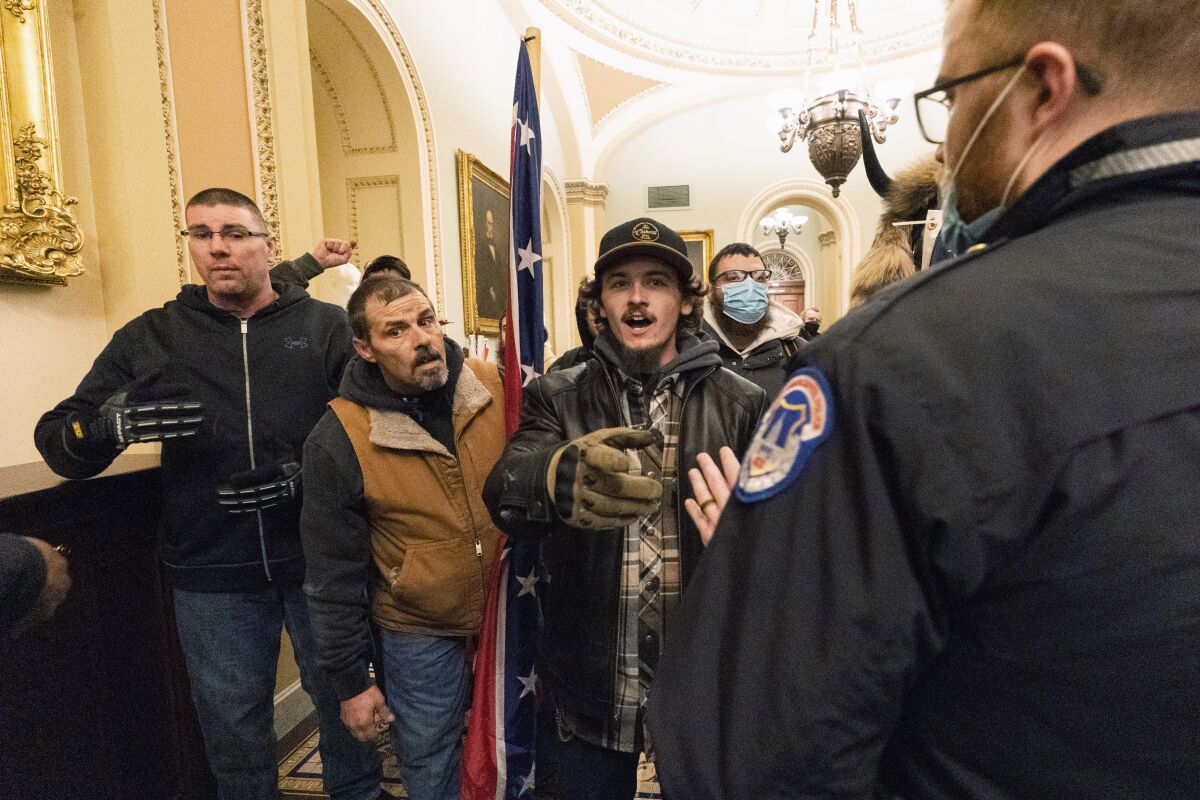 FILE - Kevin Seefried, second from left, holds a Confederate battle flag as he and other insurrectionists loyal to President Donald Trump are confronted by U.S. Capitol Police officers outside the Senate Chamber inside the Capitol in Washington, Jan. 6, 2021. A federal judge on Wednesday, June 15, 2022, convicted Kevin Seefried and his adult son Hunter Seefried of charges that they stormed the U.S. Capitol together to obstruct Congress from certifying President Joe Biden’s 2020 electoral victory. (AP Photo/Manuel Balce Ceneta, File)