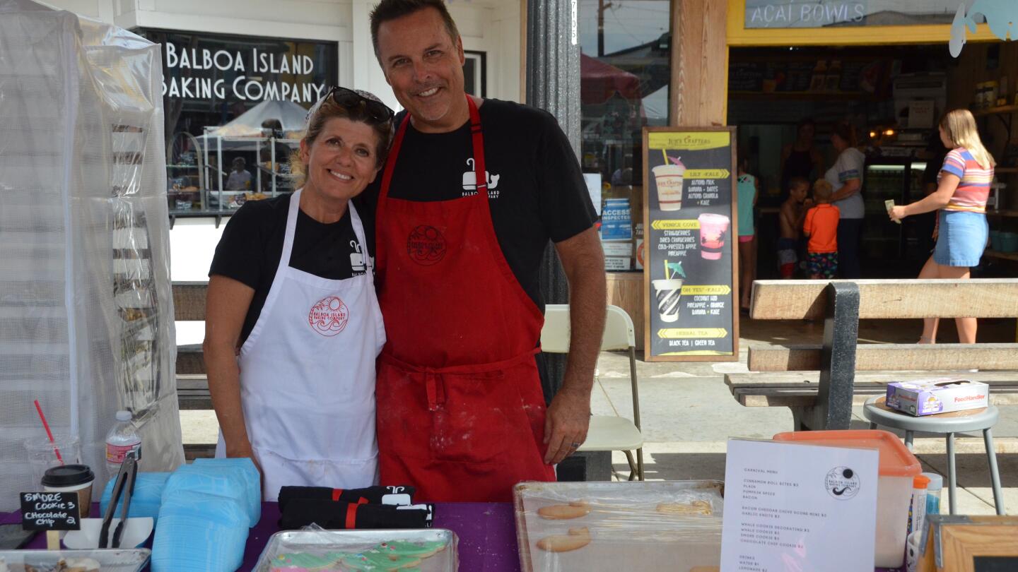 Balboa Island Baking Co. owners Denise and Brian Schuler serve iced whale cookies during the Balboa Island Carnival & Taste of the Island on Sunday.
