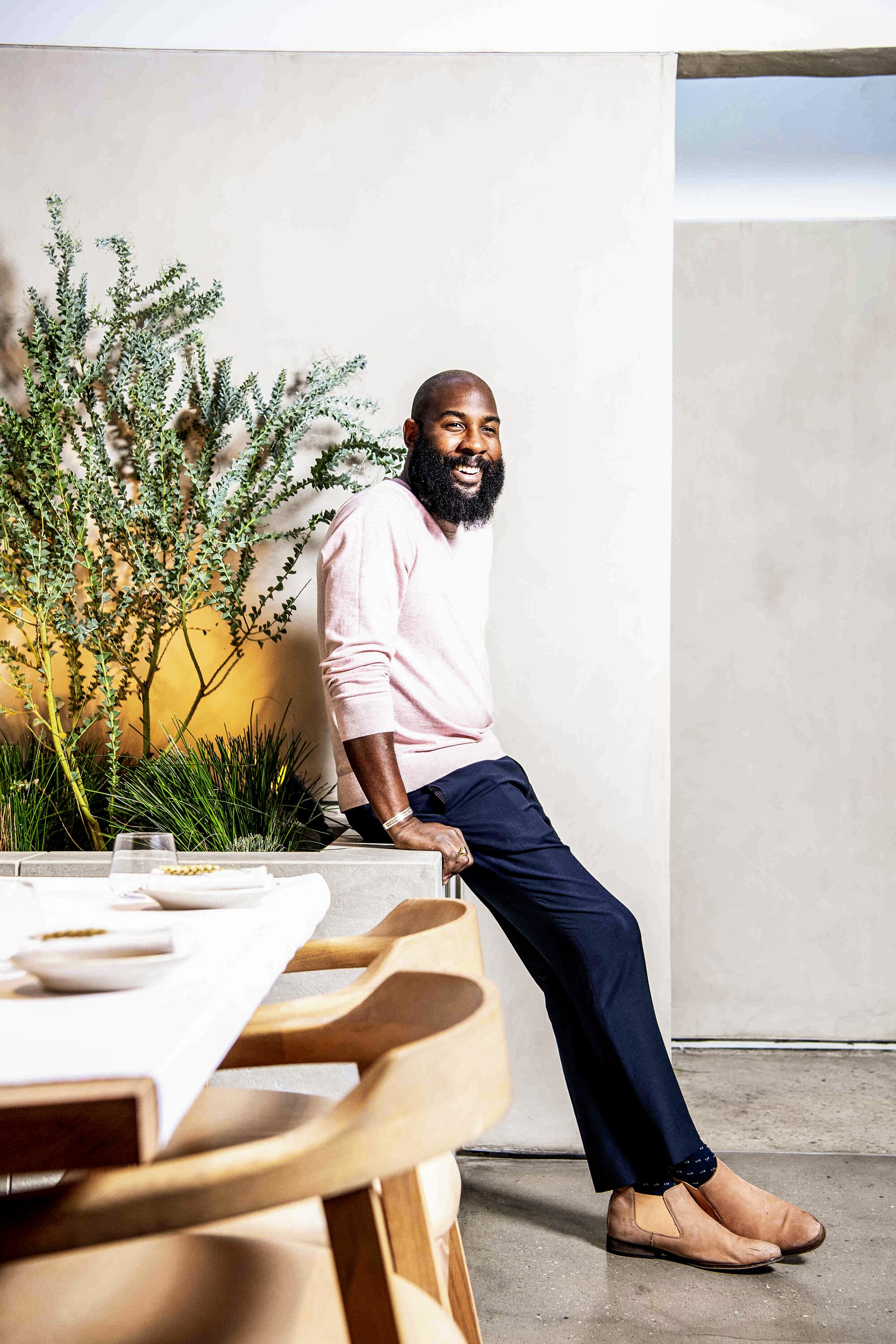 Auburn sommelier Rick Arline sits on a ledge near a set table.