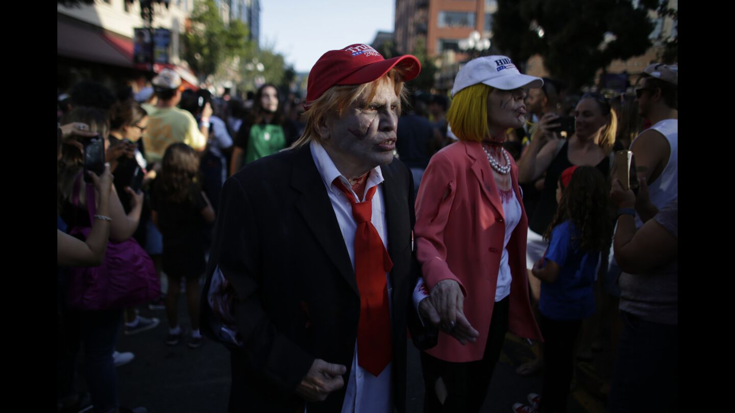 Zombie Presidential candidates Donald Trump and Hillary Clinton cosplayers walk hand in hand along Fifth Avenue during a Zombie Walk at Comic-Con 2016.