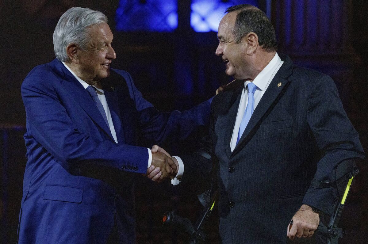Mexico's President Andres Manuel Lopez Obrador, left, and Guatemalan President Alejandro Giammatei shake hands after a joint statement at the National Palace in Guatemala City, Thursday, May 5, 2022. (AP Photo/Moises Castillo)