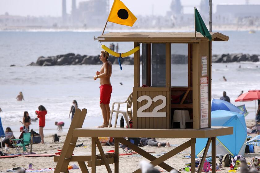 A Newport Beach lifeguard keeps an eye on beach-goers near the Newport Pier on Wednesday, July 1, 2020. Newport city council is holding an emergency meeting today to decide if it should close the beaches for the holiday after a couple of lifeguards tested positive for Covid-19.