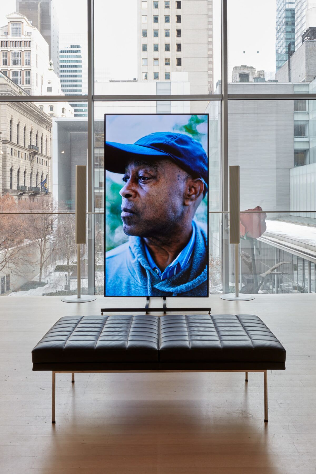 A window-lined gallery frames a video installation that show the figure of a Black man.