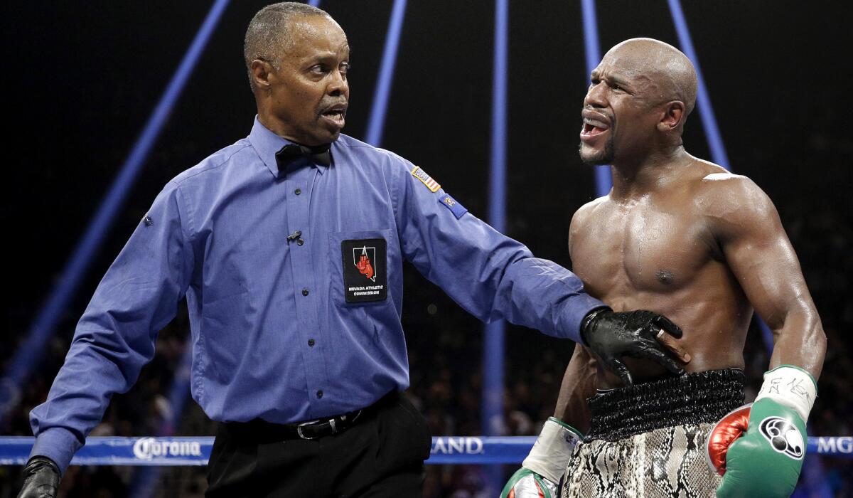 Referee Kenny Bayless holds back Floyd Mayweather during his welterweight title fight against Marcos Maidana on Sept. 13, 2014.