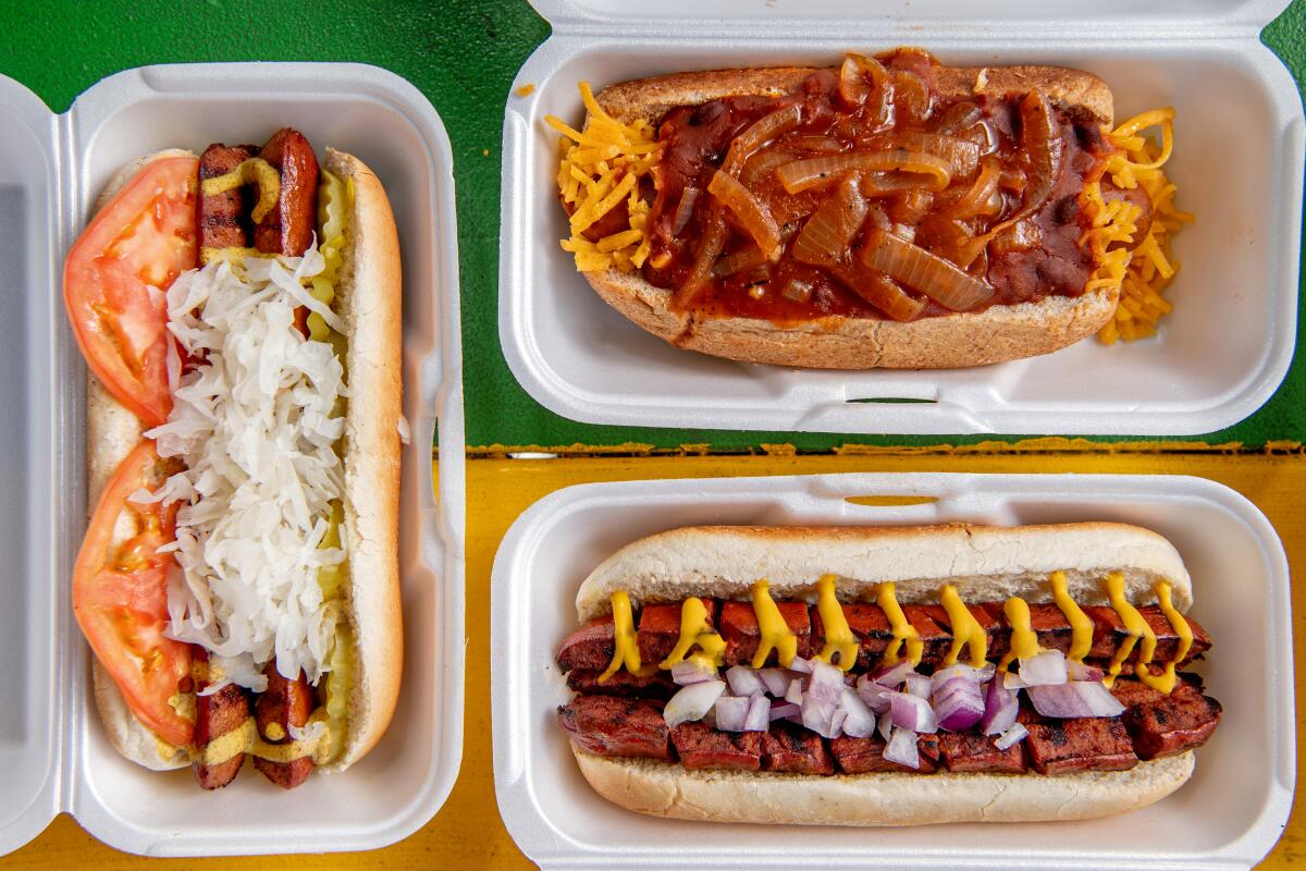 An overshot shot of a trio of hot dogs with toppings