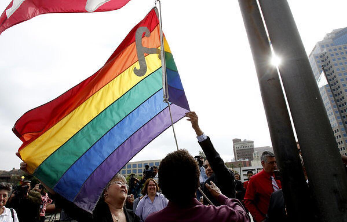 Members of the LGBT community of Long Beach raise a gay pride flag over the Long Beach Civic Center.