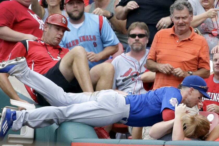 Cubs right fielder Chris Coghlan dives into the crowd to catch a foul ball hit by St. Louis Cardinals' Tommy Pham for the final out of the fifth inning.