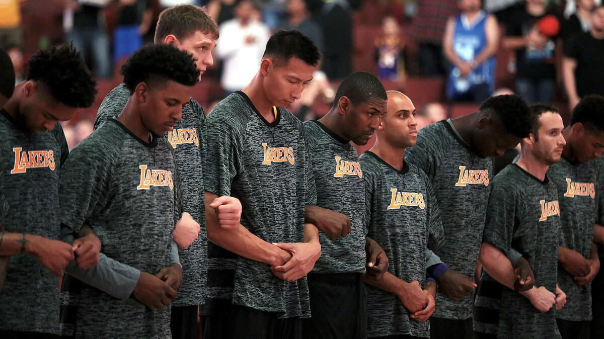 Members of the Los Angeles Lakers lock arms during the national anthem before their exhibition opener at Honda Center in Anaheim.