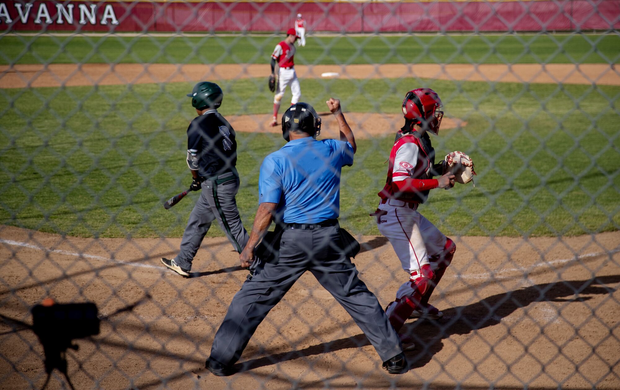Umpire Jim Trentin raises one fist during a baseball game.