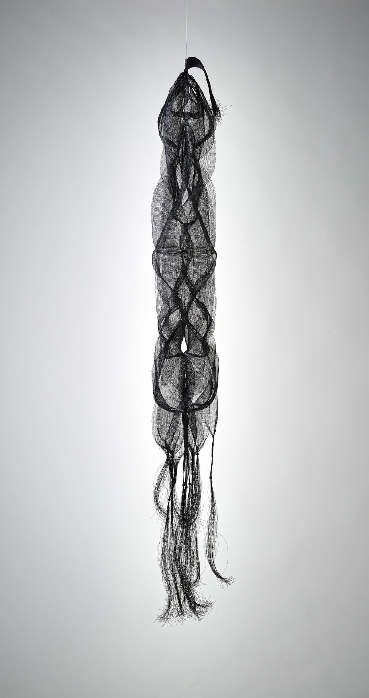 Kay Sekimachi's "Nagare I," 1967; black nylon monofilament, wood beads, plastic tubing; double, quadruple and tubular weave; 69 inches long, 13 inches diameter. (M. Lee Fatherree / Craft & Folk Art Museum)