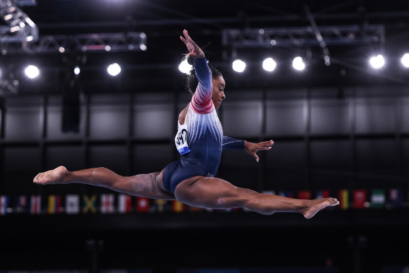 Simone Biles in midair above the balance beam.