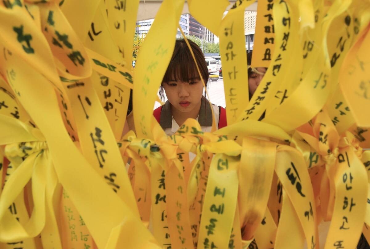 A high school student reads messages written on ribbons for victims of the sunken ferry Sewol at a memorial altar in Seoul.