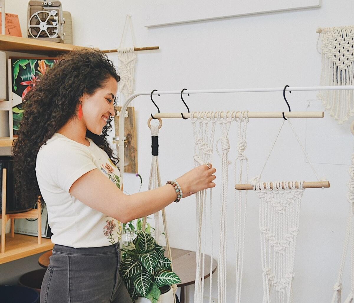 Lola Morales adjusts her white rope macramé plant hangers.