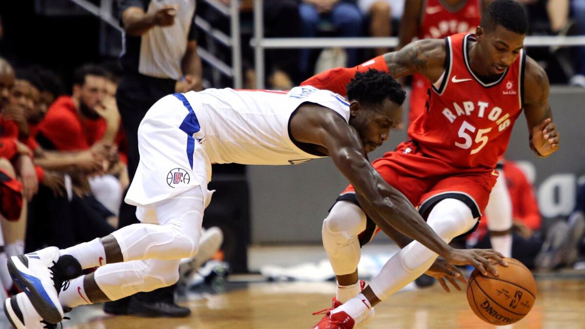 Clippers guard Patrick Beverley and Raptors guard Delon Wright fight for a loose ball during the second quarter of a preseason game.