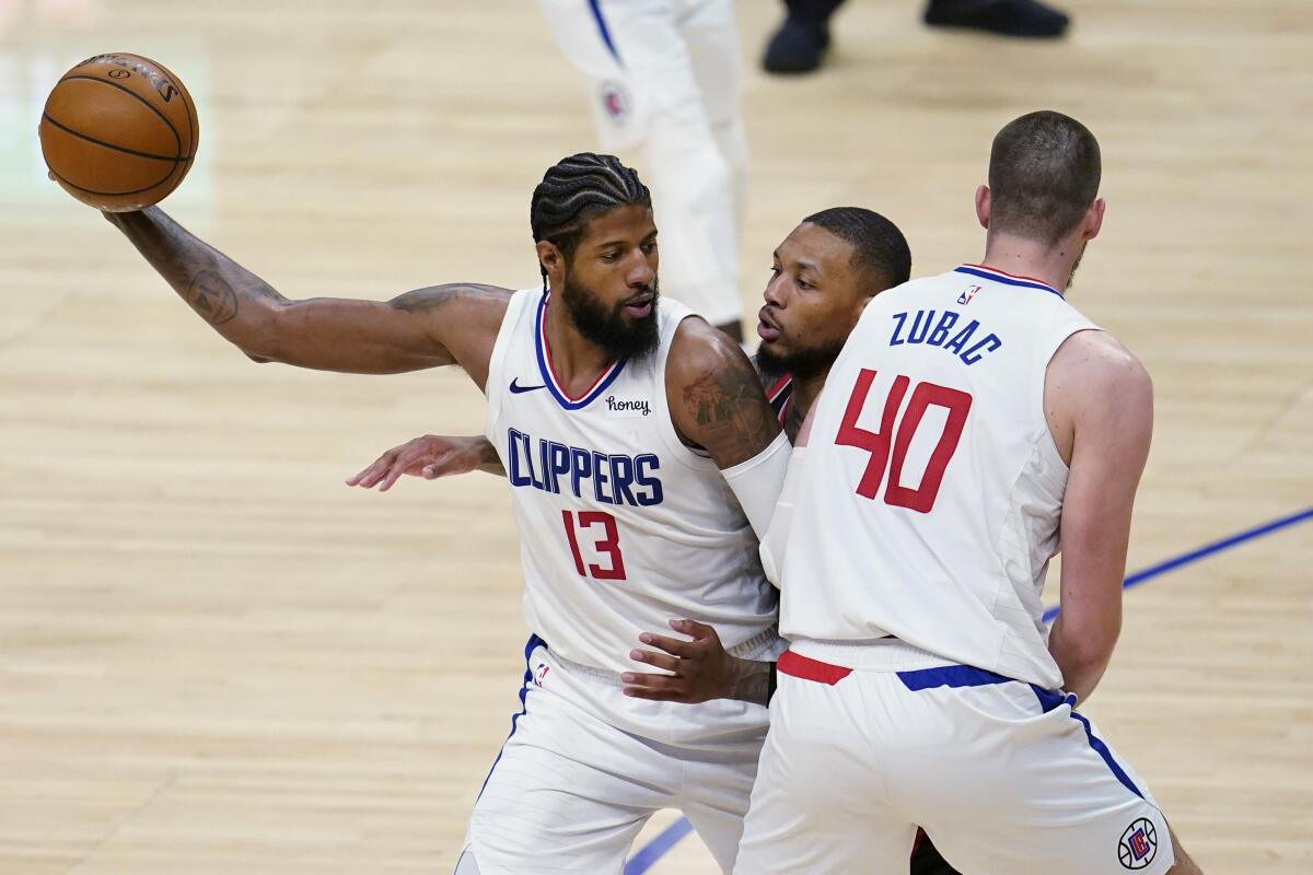 Clippers guard Paul George holds the ball as Ivica Zubac sets a screen on Portland Trail Blazers guard Damian Lillard.