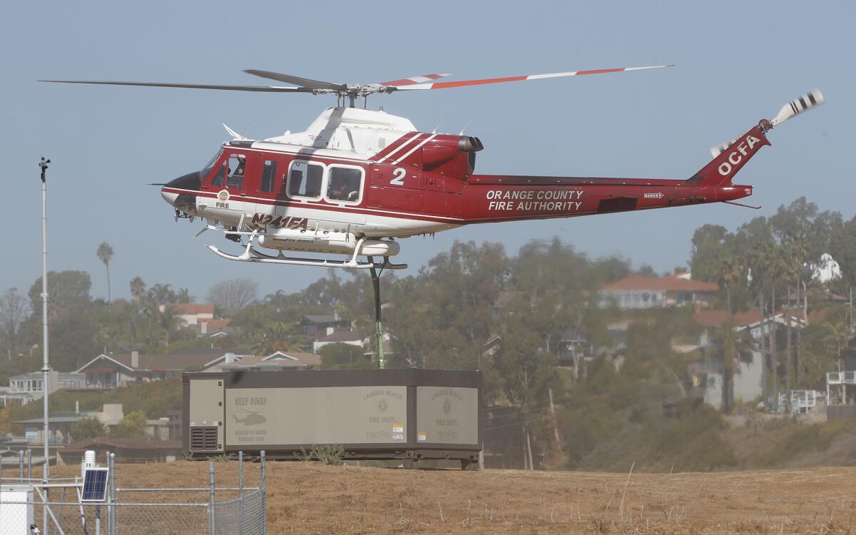 An OCFA helicopter demonstrates the water refilling system on the Arch Beach Heights fire road in Laguna Beach.
