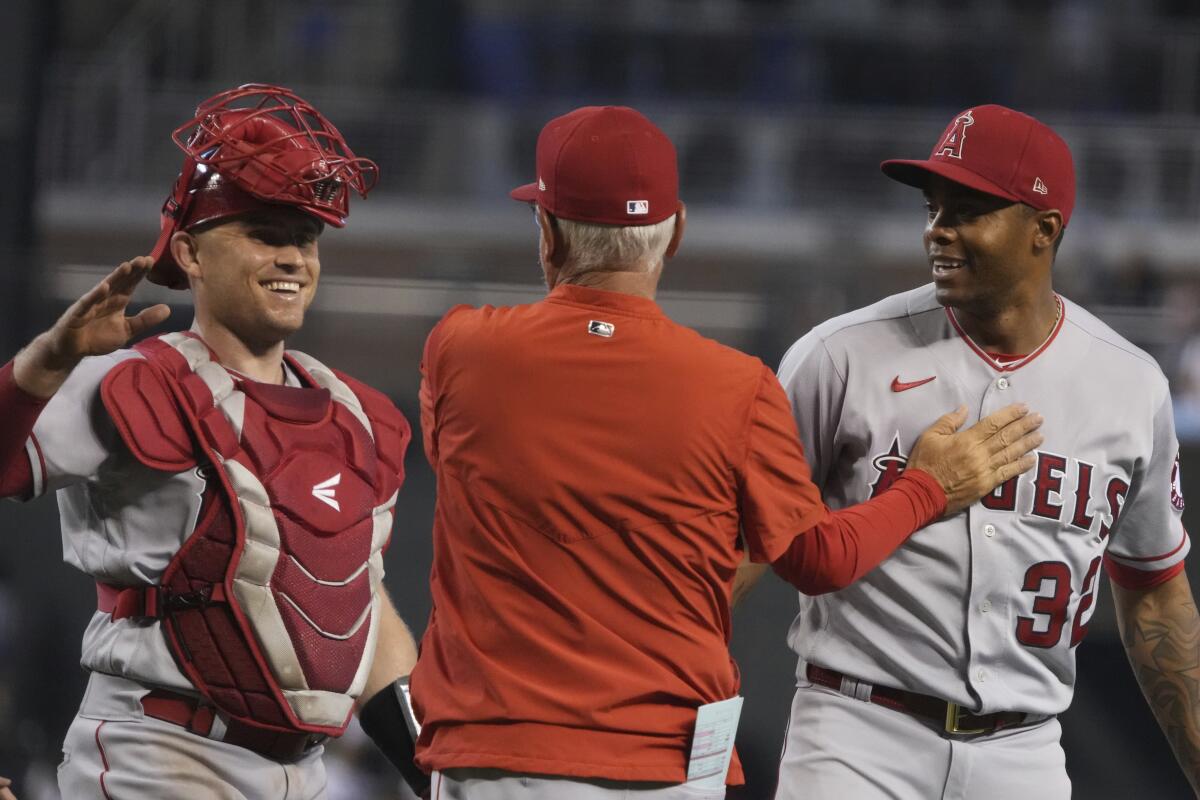Angels manager Joe Maddon, center, celebrates with catcher Max Stassi and pitcher Raisel Iglesias.