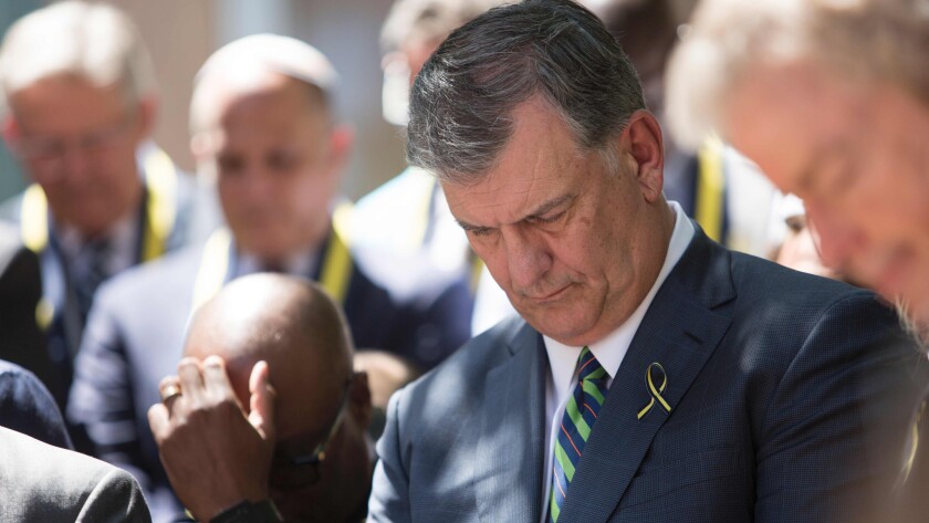 Dallas Mayor Mike Rawlings bows his head in prayer during an interfaith service Friday at Thanks-Giving Square.