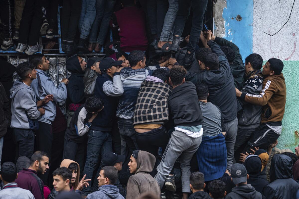 Multitudes de palestinos batallan para comprar pan de una panadería en Rafah, Franja de Gaza