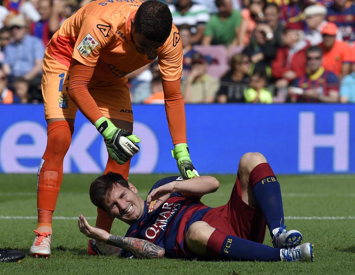 Barcelona forward Lionel Messi is checked by Las Palmas goalkeeper Javi Varas after getting injured during a Spanish league game Saturday.