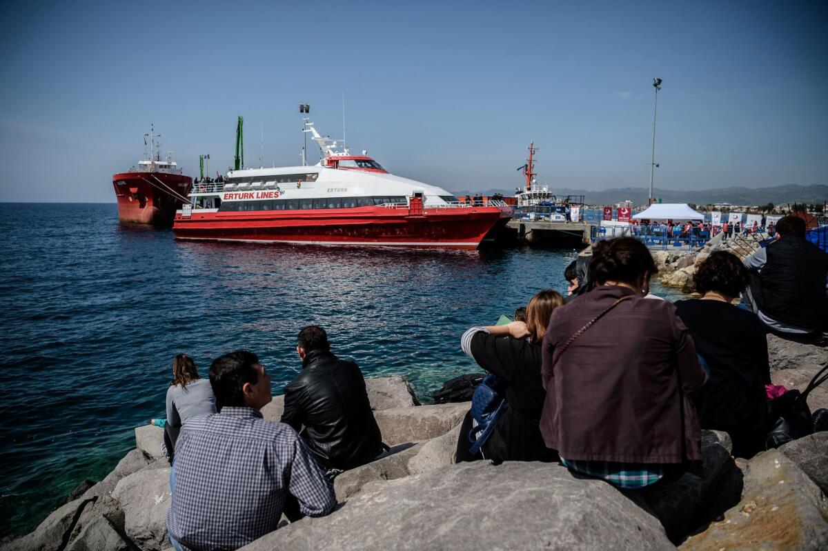 People gather on the beach as migrants deported from Greece arrive aboard a small Turkish ferry in the port of Dikili district in Izmir, Turkey, on April 4, 2016.