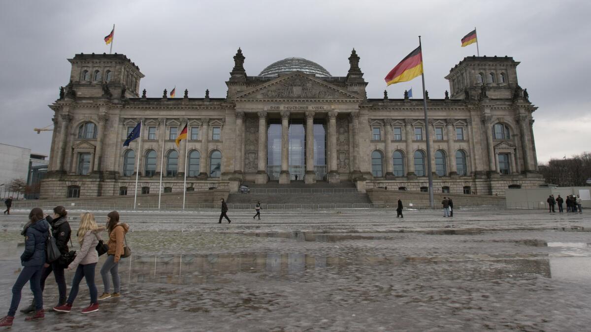 Visitors walk past the Reichstag, the home of the German federal parliament, in Berlin in 2013.