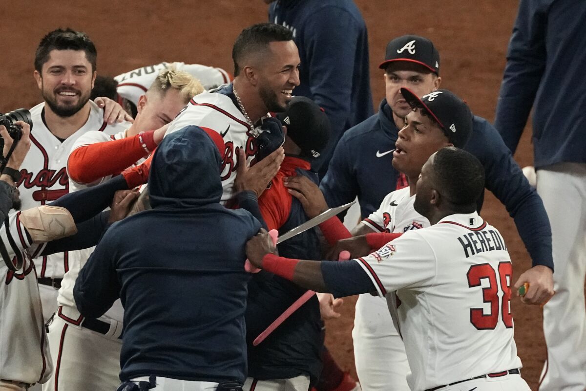 Atlanta Braves' Eddie Rosario is congratulated by teammates after hitting the game winning RBI single during the ninth inning against the Los Angeles Dodgers in Game 2 of baseball's National League Championship Series Sunday, Oct. 17, 2021, in Atlanta. The Braves defeated the Dodgers 5-4 to lead the series 2-0 games. (AP Photo/John Bazemore)