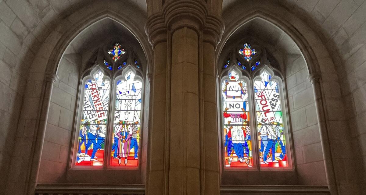 Four lancet windows framed by Gothic arches show Black people with protest signs that read "FAIRNESS" and "NO FOUL PLAY"