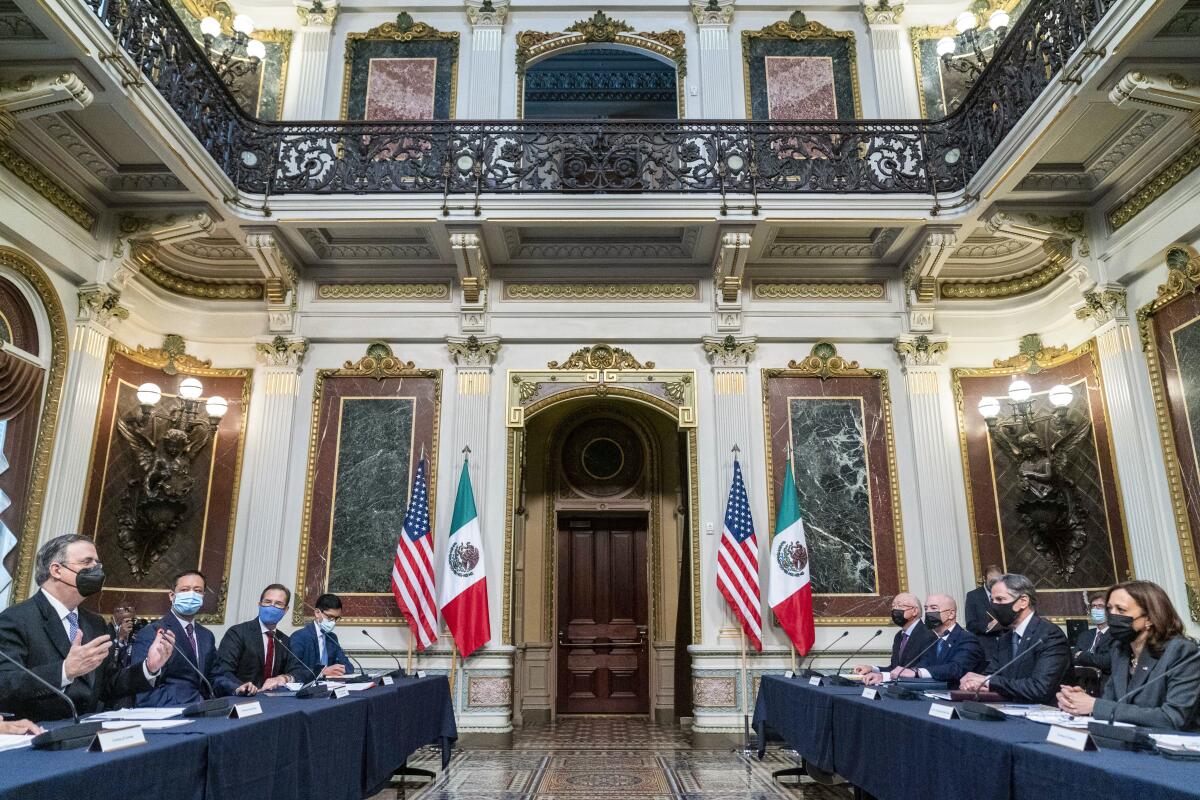 Two tables, one representing Mexico and one the U.S., face each other as officials speak