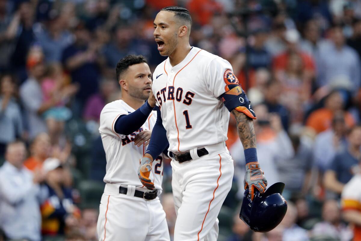 Houston Astros' Jose Altuve, left, pats Carlos Correa (1) as they celebrate Correa's home run during the second inning of a baseball game against the Oakland Athletics on Thursday, April 8, 2021, in Houston. (AP Photo/Michael Wyke)