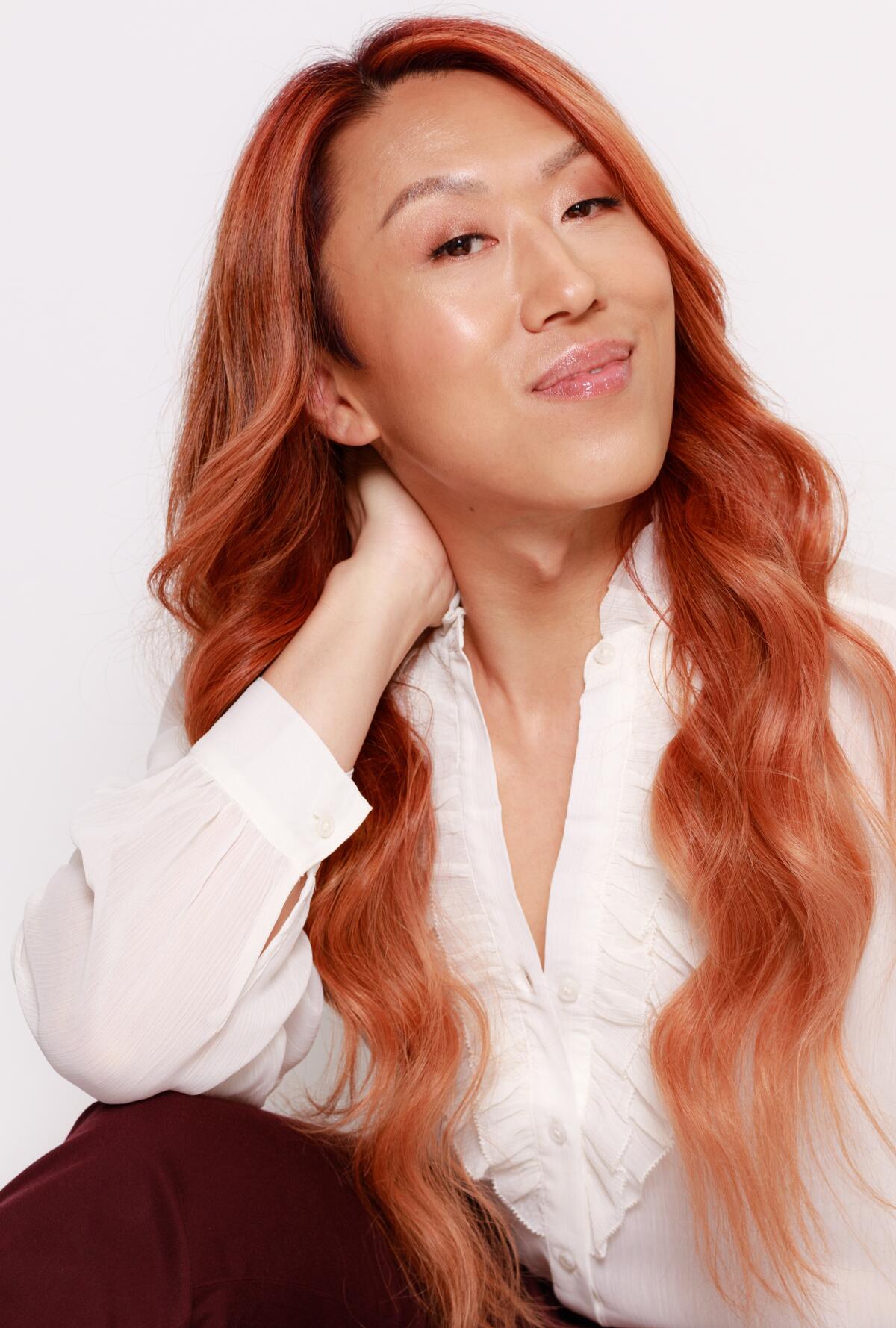 A headshot of a woman with long red hair in a white button-down shirt.